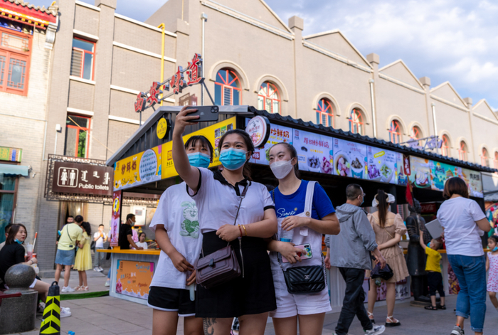 2022年6月18日晚，呼和浩特市玉泉区，游客在塞上老街区块一家快闪店前拍照留影。