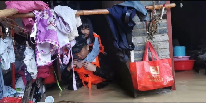 洪水没过家门，救援人员背起被困女孩。张陈宇 摄