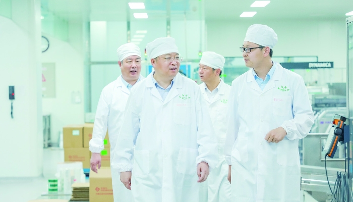 图③：张贵民在鲁南制药生产车间向管理人员了解生产情况。