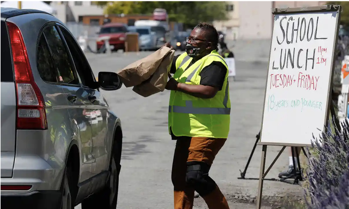 ↑2020年4月，一名志愿者在发放学校午餐