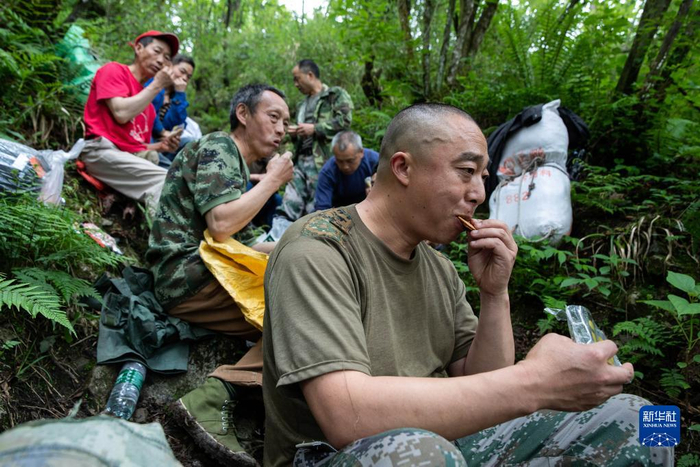 大熊猫国家公园彭州管护总站的巡护员在巡山途中吃干粮（6月3日摄）。新华社记者 江宏景 摄