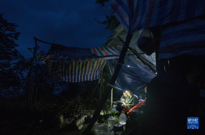 大熊猫国家公园彭州管护总站的巡护员宋自强（中）在宿营地和同事讨论巡护路线（6月4日摄）。新华社记者 江宏景 摄