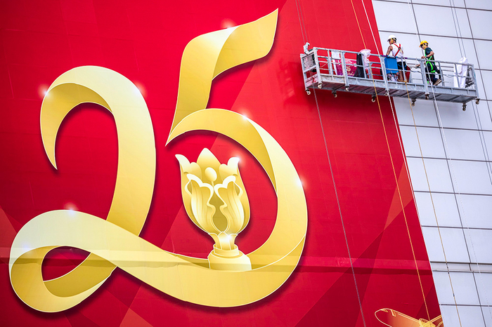 2022年6月13日，中国香港，工人们在一栋建筑的侧面张贴了一张巨型海报，庆祝香港特别行政区成立25周年。