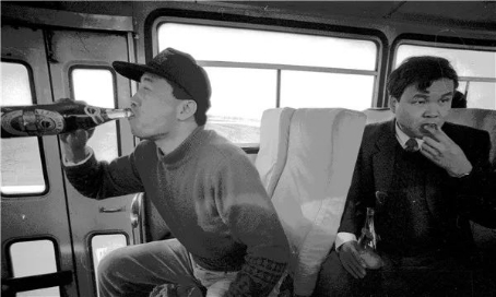 1995年从青岛到济南的长途车上，一位青岛摄影家正在“吹瓶”。张建华摄