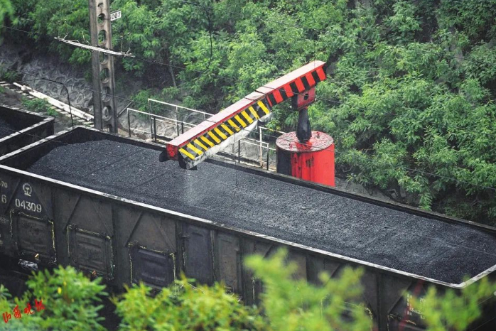 装满煤驶出工业园的列车，正被喷洒抑尘剂