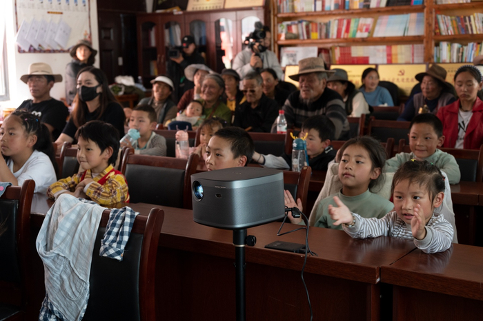 　　图：雨托村的老人和孩子们用投影观看大屏电影