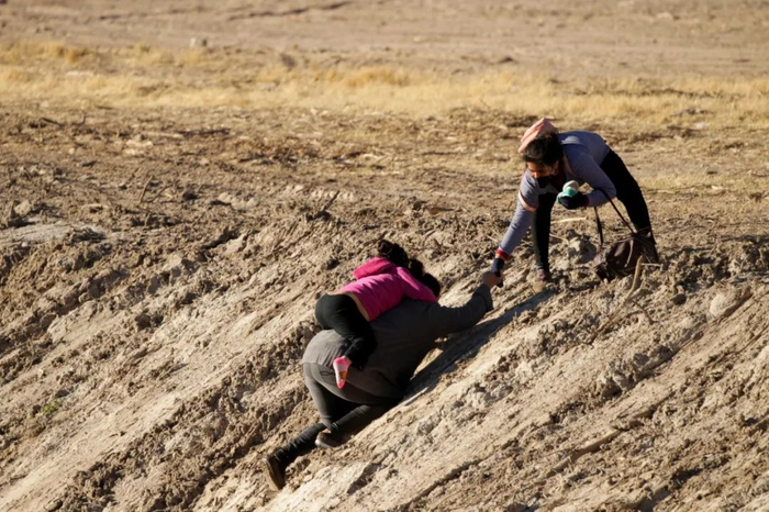 ·一男一女带着孩子爬上格兰德河岸。