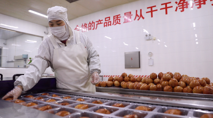 在保定市王成兰食品有限公司包装车间内，生产人员正在对罗汉肚进行拉伸膜包装。李沭星摄