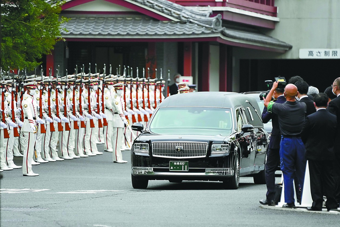 12日，载有安倍遗体的灵车在仪仗队和随从之间穿过。（视觉中国）