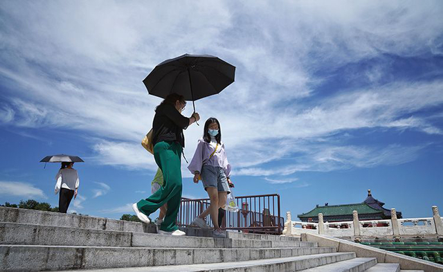 7月18日，天坛公园里，游客撑遮阳伞游览。新京报记者 浦峰 摄