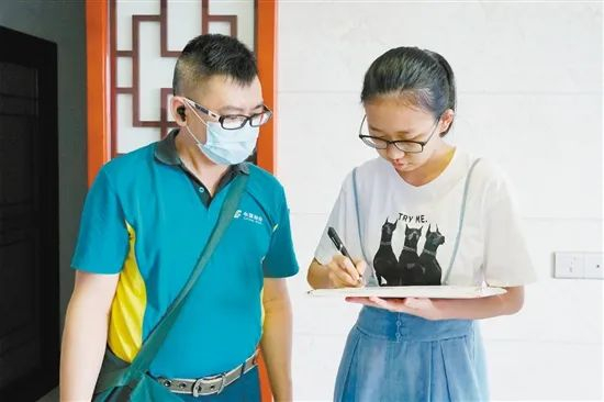 邮政工作人员确认考生身份后，把录取通知书送到康可欣手中。