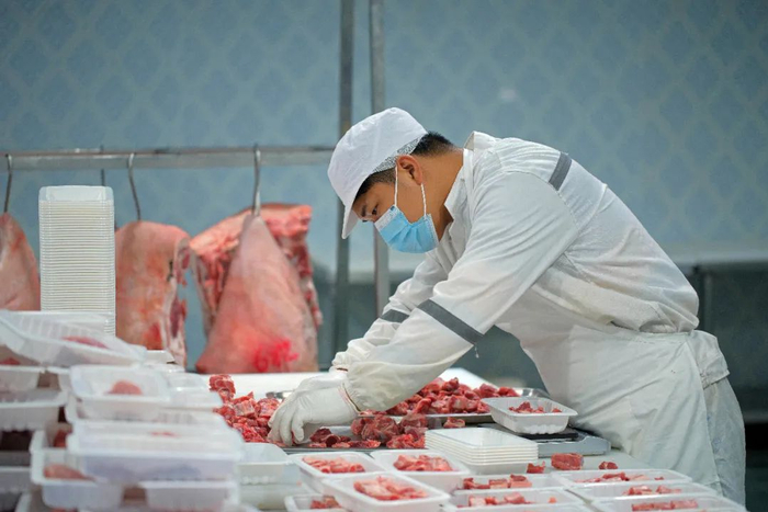 乐家庄的深圳加工厂里，刀手在分割猪肉（张雷 摄）