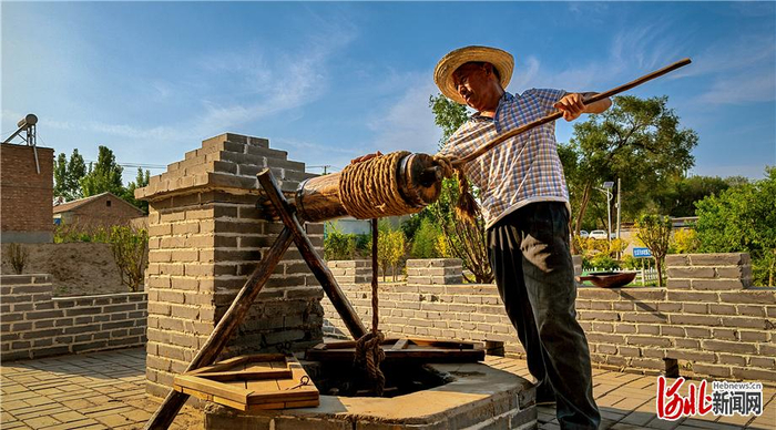 日前，一位来村中务工的人员在感受油坊口村的古井与辘轳。 通讯员郑延涛摄