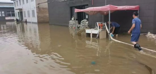 洪涝后，王家堡村工厂的工人用水泵抽水排洪。图片来源：张志明