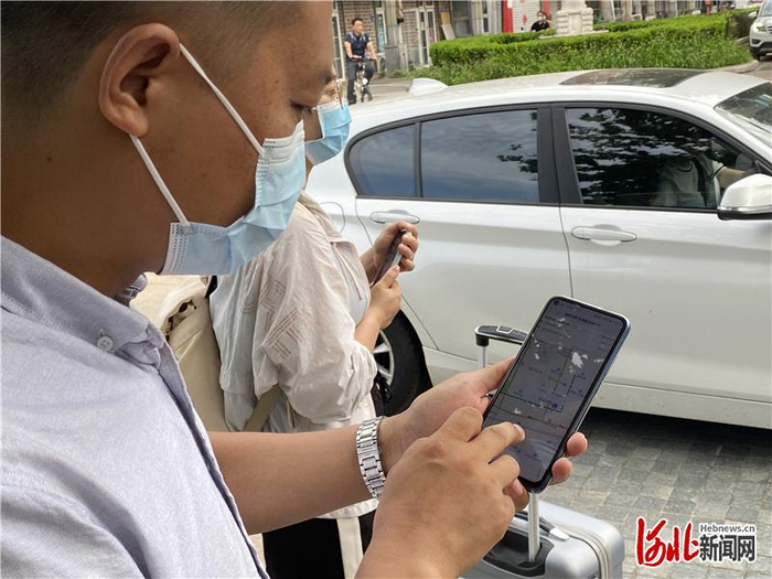 7月25日，在三河市星河园小区门口，乘客通过“京津冀定制快巴”微信公众号实时观看车辆行进位置。通讯员高澍摄