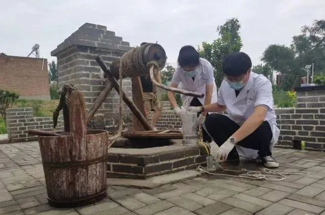 两名工作人员在对油坊口村古井水质进行监测检验。