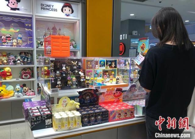 资料图：消费者在泡泡玛特门店挑选Molly盲盒。 中新网 左宇坤 摄
