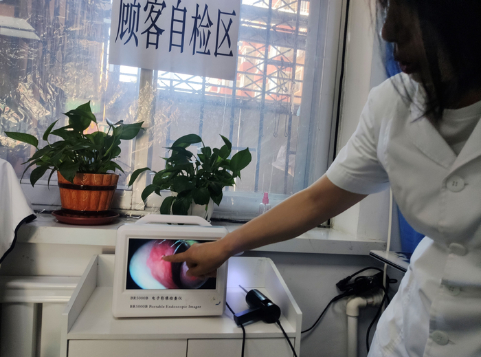 身穿白大褂的女子使用电子影像设备为记者做鼻腔检查。李洪涛/摄