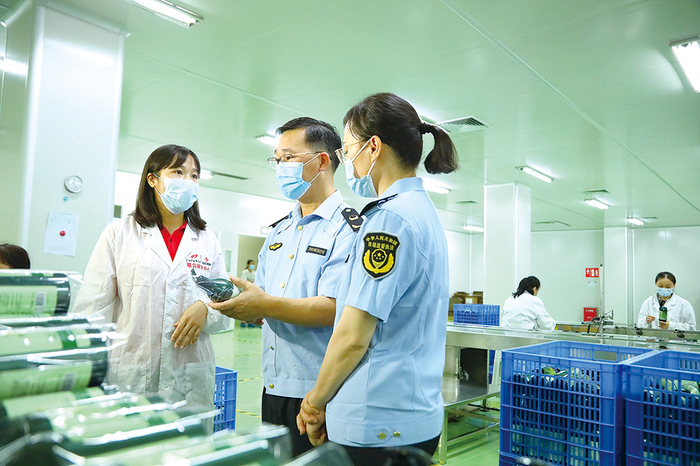 南宁市市场监管局经开分局工作人员在企业生产车间了解化妆品外包装情况。