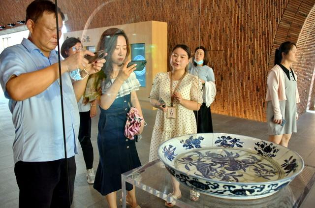 8月24日，参观者在景德镇御窑厂遗址观赏出土陶器。摄影/章轲