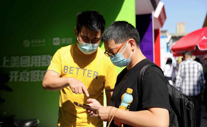 图为工作人员向观众介绍数字人民币低碳卡硬件钱包