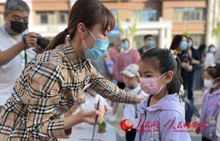 雄安容和佳泰幼儿园老师正在为孩子们进行“朱砂启智”，寓意新学期开启新智慧。雄安容和佳泰幼儿园供图