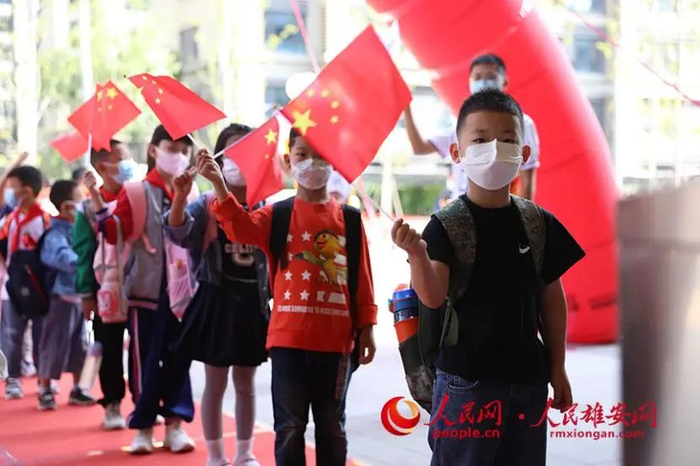 雄安容和海棠小学，孩子们手中挥舞着入学前爱国主义教育收到的国旗准备进入学校。李兆民摄