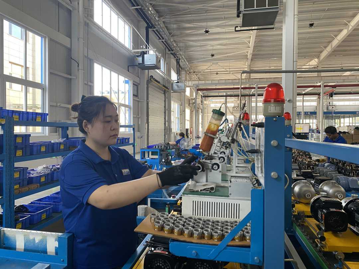 三河市同飞制冷股份有限公司车间内，工作人员正在进行螺纹密封胶涂胶操作。高澍摄