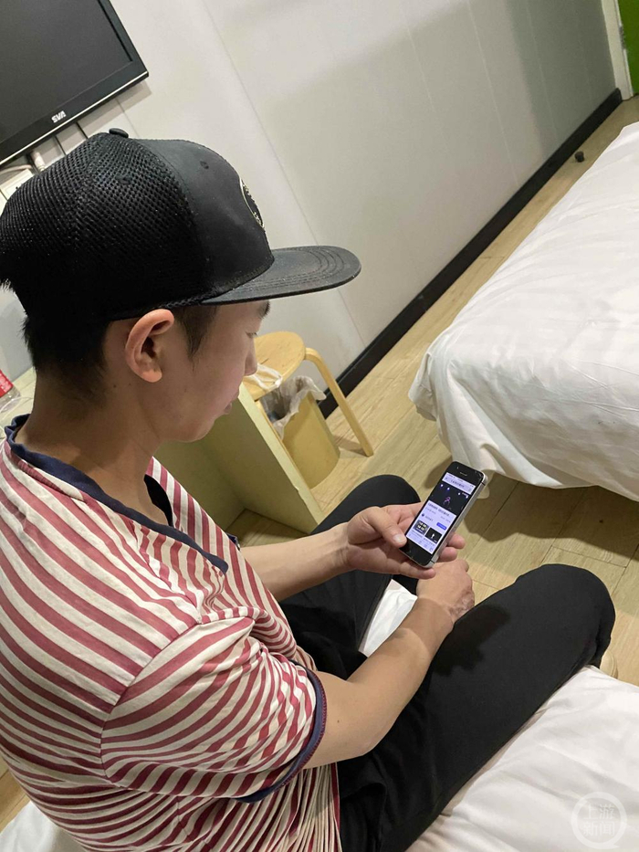▲2021年5月，西安一宾馆，庞麦郎用手机看自己的演出视频。摄影/上游新闻记者 汪璟璟
