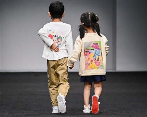 　　图：在KIDS WEAR童装发布秀上展示美术作品的孩子