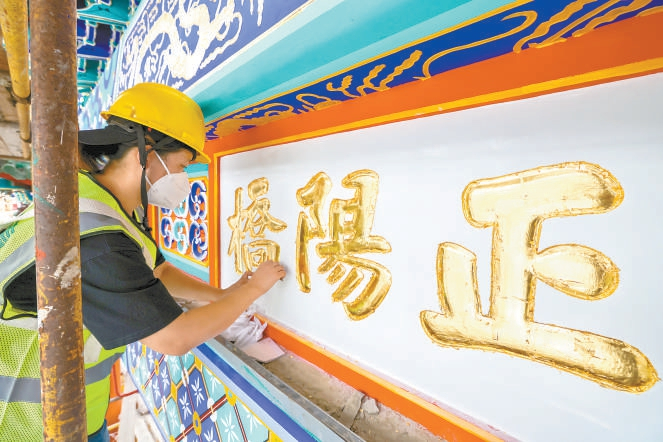 昨天，前门五牌楼正中牌匾上“正阳桥”三个字开始“贴金”。本报记者 邓伟摄