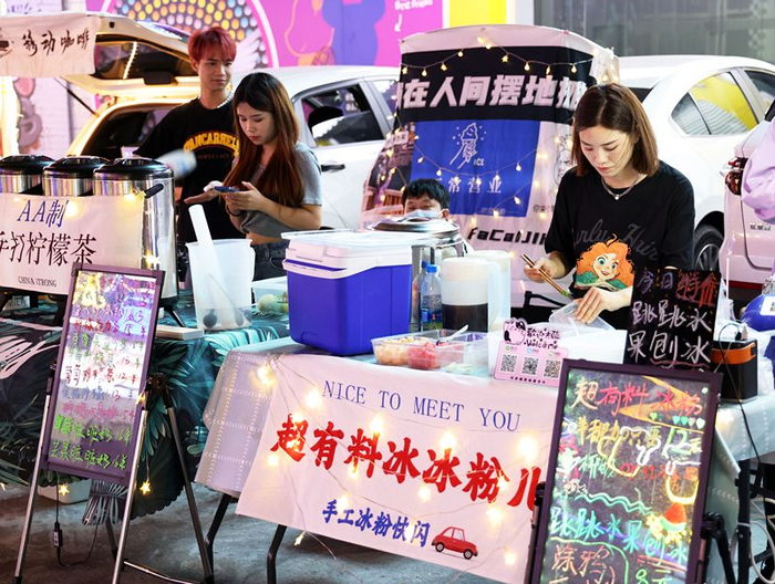 ▲南区灯光美食城车摊夜市霓虹闪烁，奶茶档、精品档、果汁档整齐排列。 记者 文波