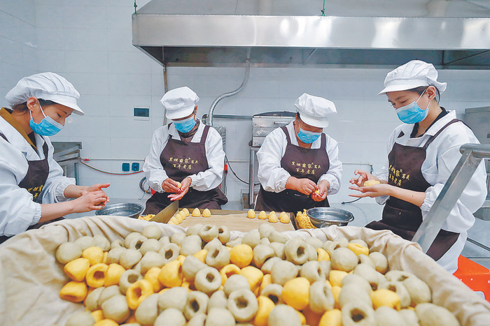     图为在里坦镇薛家窝头非遗体验馆生产车间内，工作人员在制作窝头。    本报记者 陈童 摄