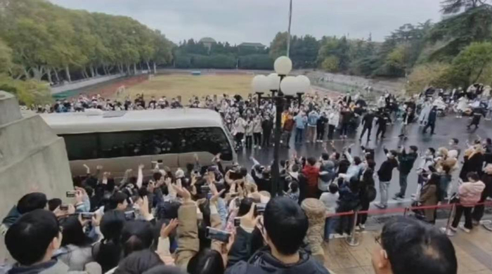 学生们挥手目送窦贤康乘车离校。视频截图