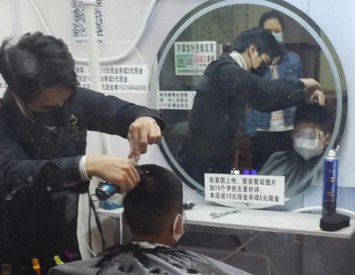 妈妈带着两个孩子来理发。时代财经 摄