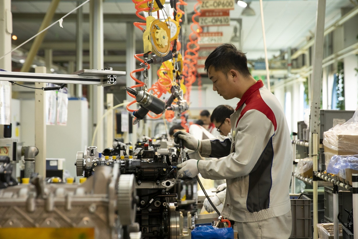 图为工人正井然有序地组装发动机。