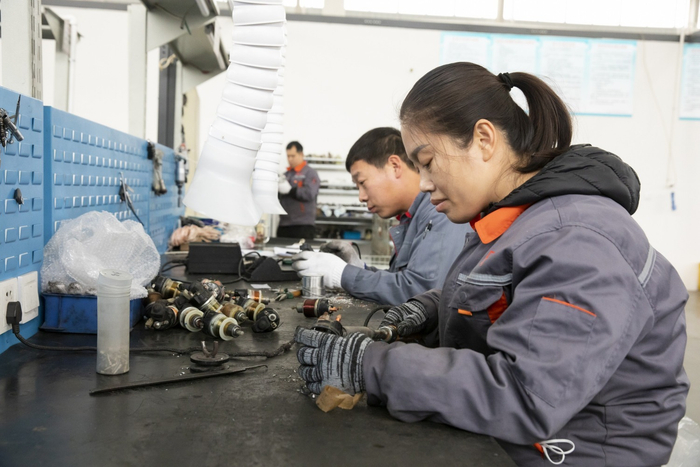 图为工人正在组装起动机开关。