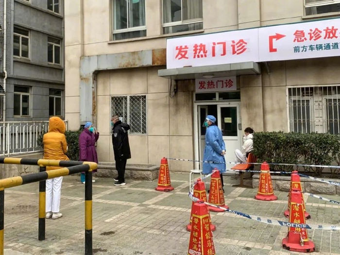 2022年12月12日，北京同仁医院西区，发热门诊外，患者候诊，医护人员值守。新京报记者 王嘉宁 摄