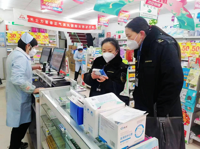 执法人员对药店进行检查。  