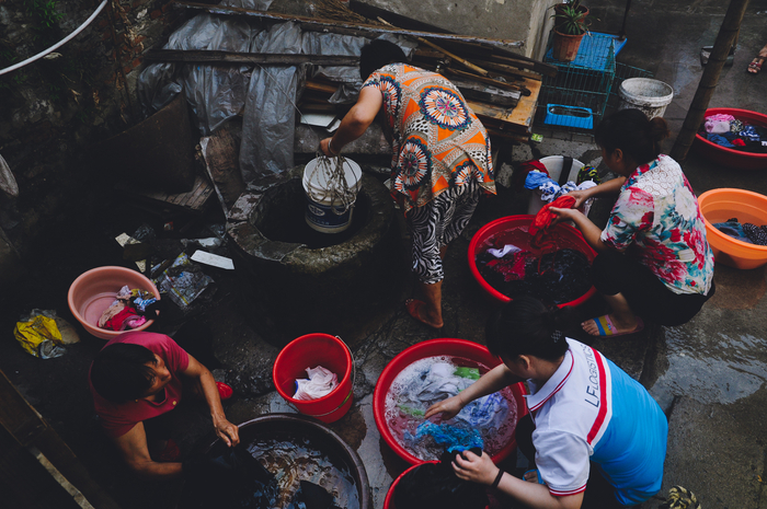 由于缺少公共管网，居民只能拿着大脸盆打井水洗衣服