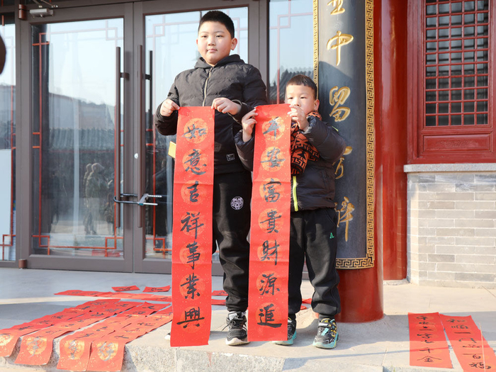 ↑1月4日，在石家庄市灵寿县迎新春送春联活动现场，孩子展示对联。（杨敏 摄）