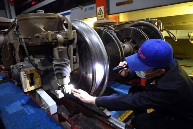 专项修车间技术组组长白冰用手电观察列车钢轮的磨损情况。 新京报记者 王贵彬 摄