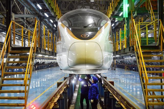 两名工作人员正在检查复兴号动车组车底。 新京报记者 王贵彬 摄