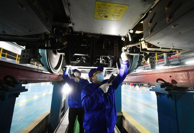 两名工作人员正在检查复兴号动车组车底。 新京报记者 王贵彬 摄