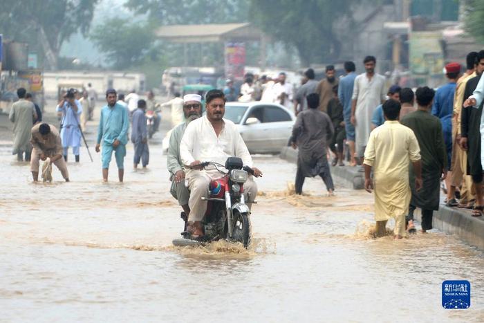 8月27日，人们在巴基斯坦贾尔瑟达涉水出行。 新华社发 卡尤姆 摄