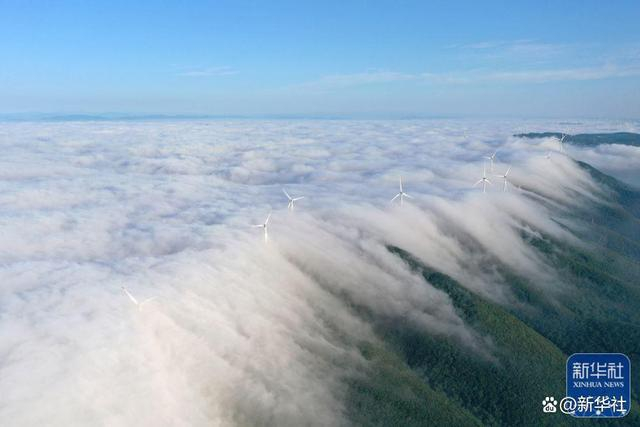 ↑2022年5月29日，湖北省荆门市城郊圣境山现壮观的瀑布云景观，风机在云中若隐若现（无人机照片）。新华社发（彭琦 摄）