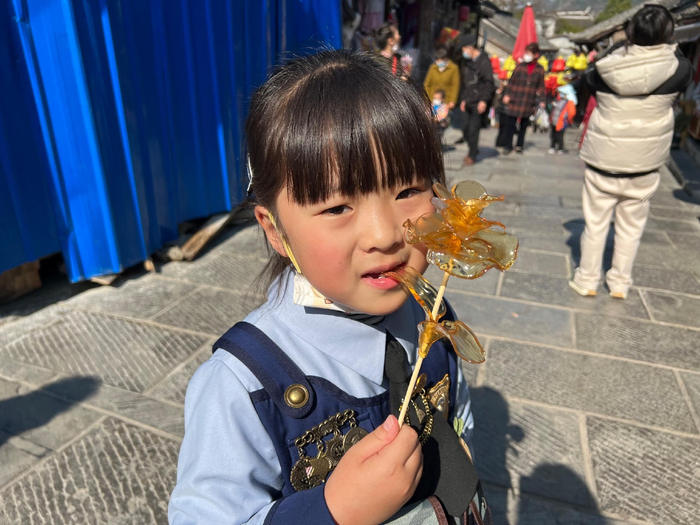 曹女士女儿拿着刚刚买的“玫瑰花”糖画