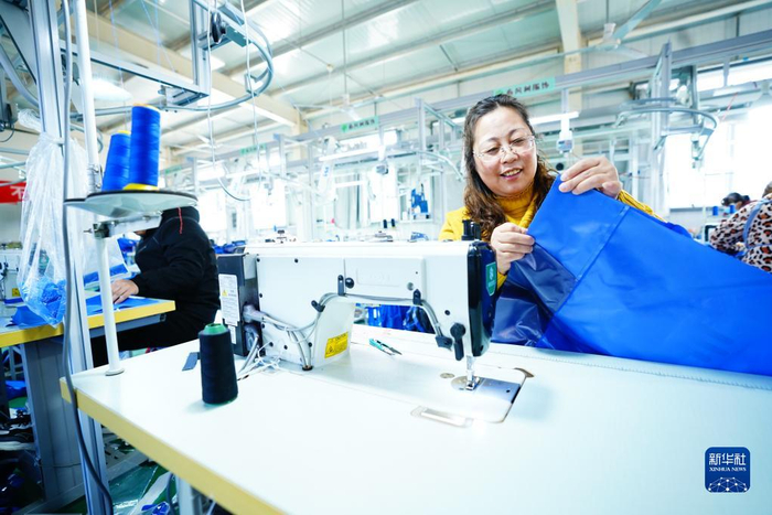 2022年12月26日，在河北省阜平县大教厂村的春风树服饰有限公司手工业生产车间，村民在做校服。新华社发（李秀芹 摄）