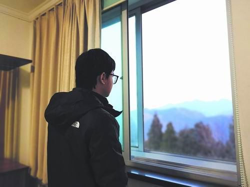 接受采访时，向铭拉开窗帘，窗外的山景依旧美丽。倪思洁/摄