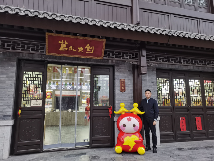 王晓明和“莒宝宝”站在莒礼文创门店前 图片来源：受访者供图